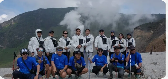 Gathering perusahaan dengan jaket Antarestar putih dan kaos biru di kawah gunung